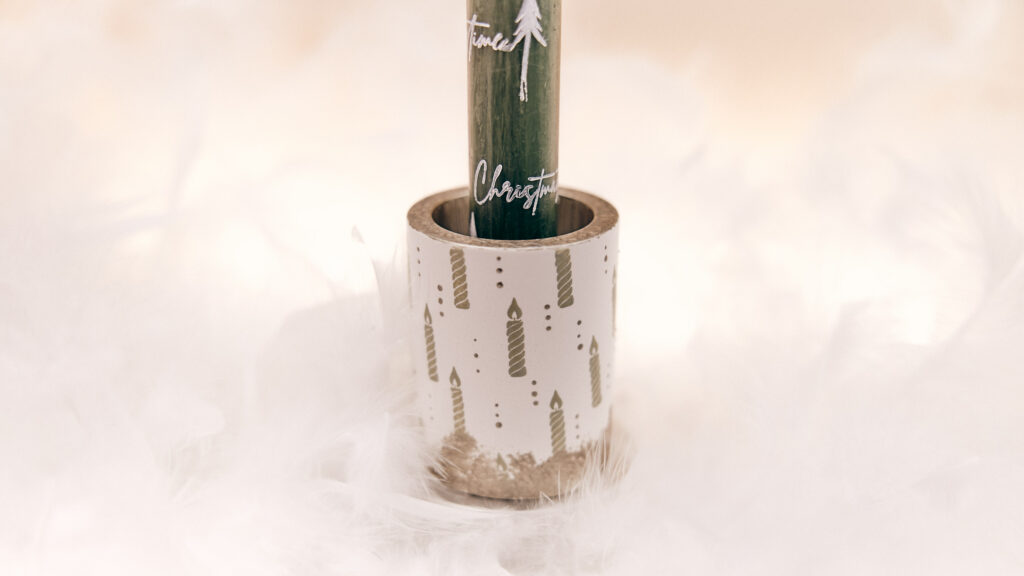 Borstenpinsel, graue Farben, verzierter Kerzenhalter mit Adventskerze Stempelmotiv, umgeben von Bastelzubehör.