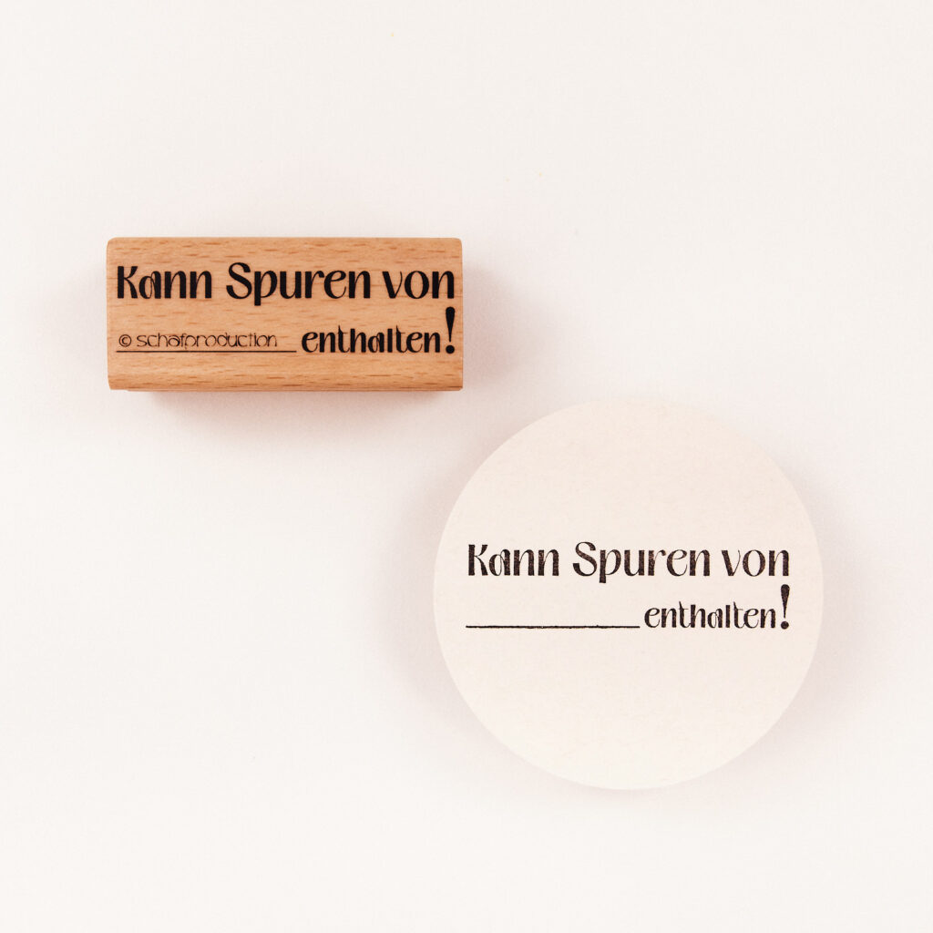 Ein Holzstempel mit dem Schriftzug "Kann Spuren von .... enthalten“ - ideal für kreative Geschenkverpackungen.